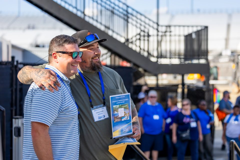 Image of a team member accepting a prize from VP of Product Support David Welch. Both employees are smiling and facing the right. 