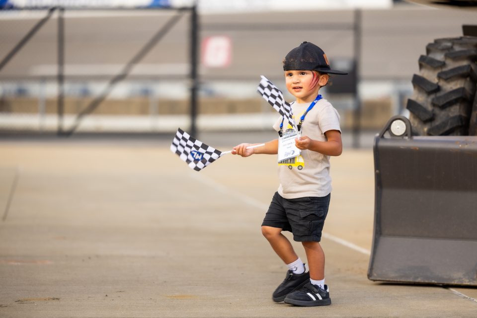 Image of a younger person at our employee appreciation day holding two McClung-Logan flags.