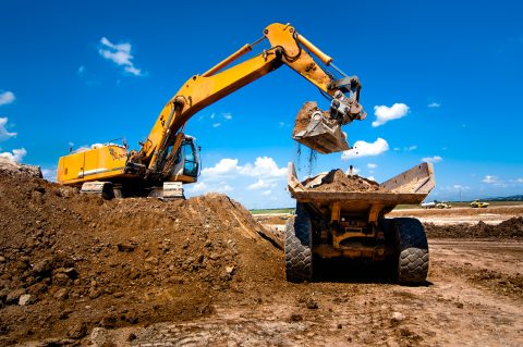 Industrial track loader excavator moving earth and unloading int